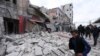 FILE - People walk past debris following airstrikes by government forces, in the town of Ariha, Idlib province, Syria, Jan. 15, 2020. 