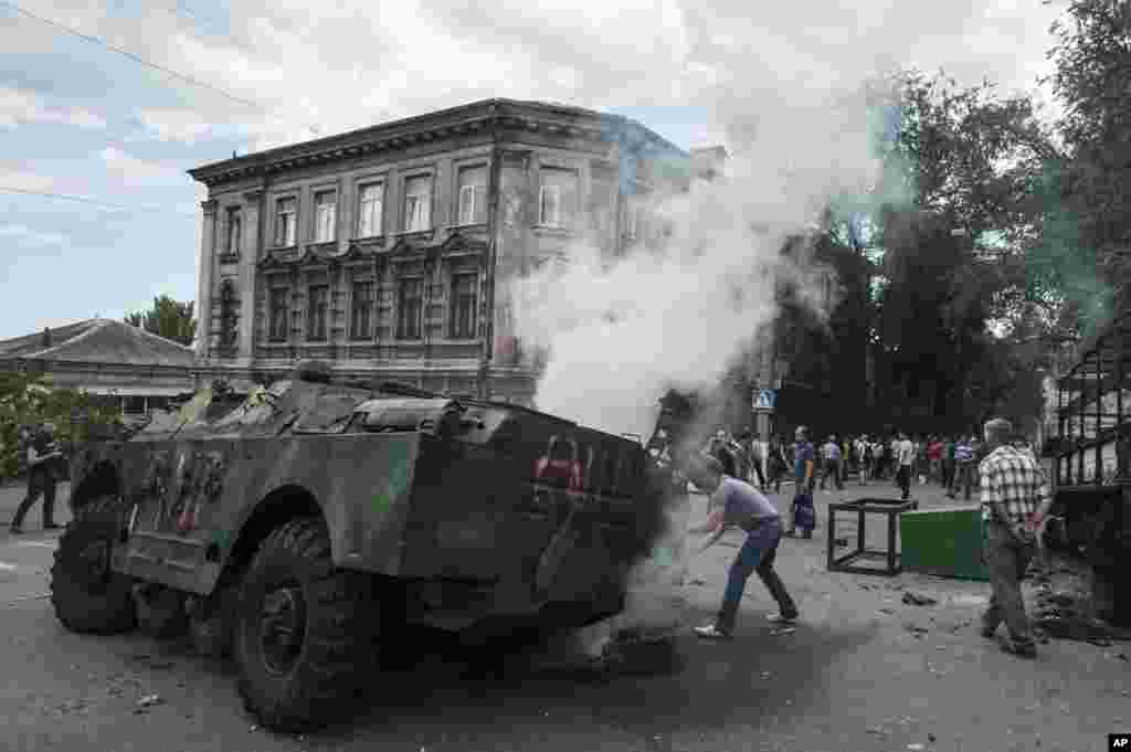 Local citizens gather around a burning military vehicle at a site of a battle between Ukrainian troops and pro-Russian fighters in Mariupol, eastern Ukraine.
