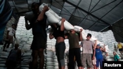 Para pekerja pabrik gula di Sidoarjo, Jawa Timur, mengangkut karung-karung berisi gula dari gudang ke truk untuk didistribusikan. (Foto: Dok)