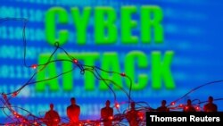 LED lights and toy figures are seen in front of displayed binary code and words "Cyber Attack." (Reuters)