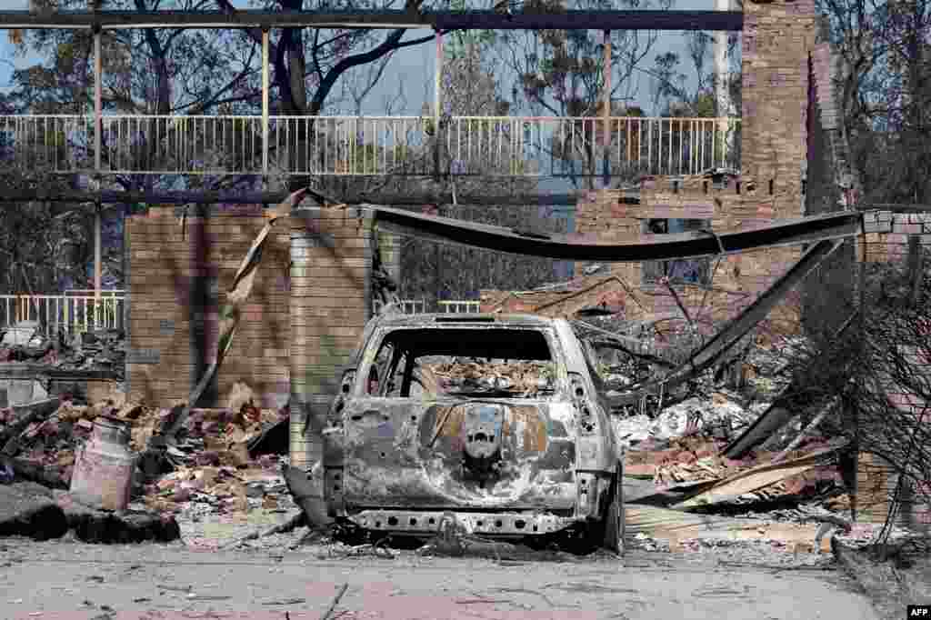 Sebuah mobil yang terbakar tampak di depan rumah yang rusak akibat kebakaran semak di Winmalee, Blue Mountains, Sydney. Kebakaran semak belukar itu melumpuhkan komunitas di sekitarnya dan menghancurkan ratusan rumah di wilayah Australia tenggara itu di mana di puluhan kebakaran masih belum bisa dikendalikan.
