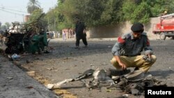 A police officer collects evidence from the site of a bomb attack on a Frontier Corps (FC) convoy in Peshawar, Sept. 23, 2014. 