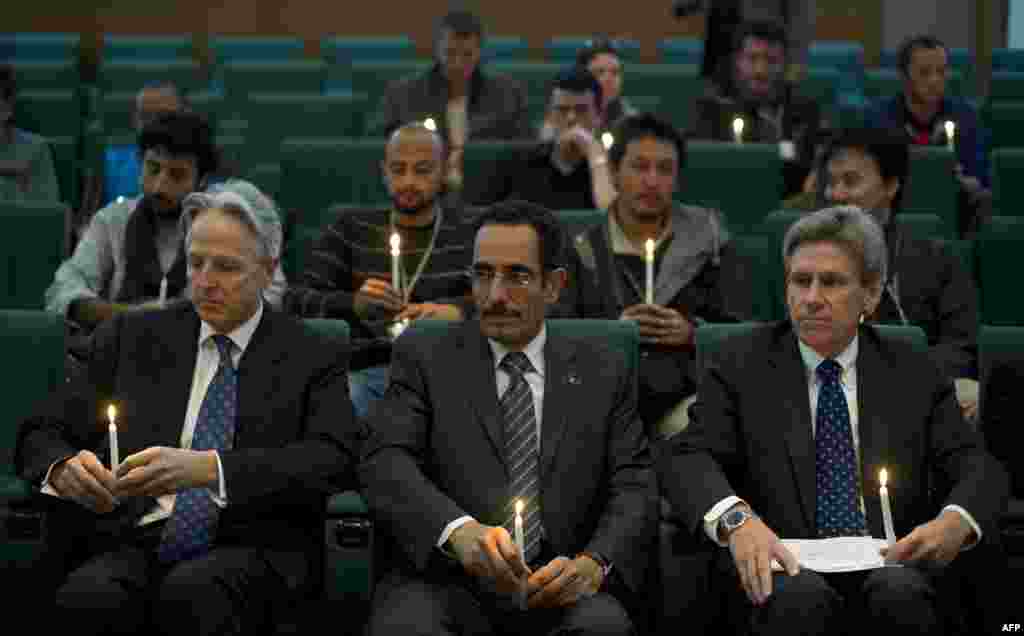 Chris Stevens (à droite), émissaire américain dans la zone sous contrôle des rebelles libyens, l'émissaire britannique Christopher Prentice (à gauche) et le vice-président du Conseil national de transition libyen Abdul Hafiz Ghoqa tenant des bougies lors d'une cérémonie en mémoire du journaliste Tim Hetherington, tué en Libye