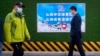 People walk past a poster promoting the 2022 Winter Olympics that reads 'Carry forward the Chinese sports spirit, promote sportsmanship' in Beijing, Dec. 8, 2021.