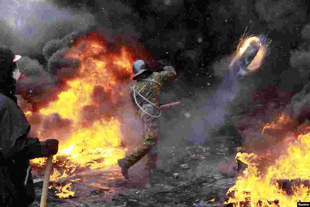 Demonstran anti pemerintah melemparkan ban yang terbakar ke arah polisi anti huru-hara Ukraina dalam bentrokan di ibukota Kyiv.