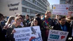 Madaktari wa ngazi ya chini wakiwa wameshikilia mabango wakishiriki katika kuanza kwa mgomo nje ya Hospitali ya St Thomas' jijini London, Jumanne, Aprili 26, 2016.
