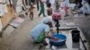 FILE - A woman who says she belongs to the Rohingya community from Myanmar, washes clothes in a New Delhi camp, September 13, 2014.