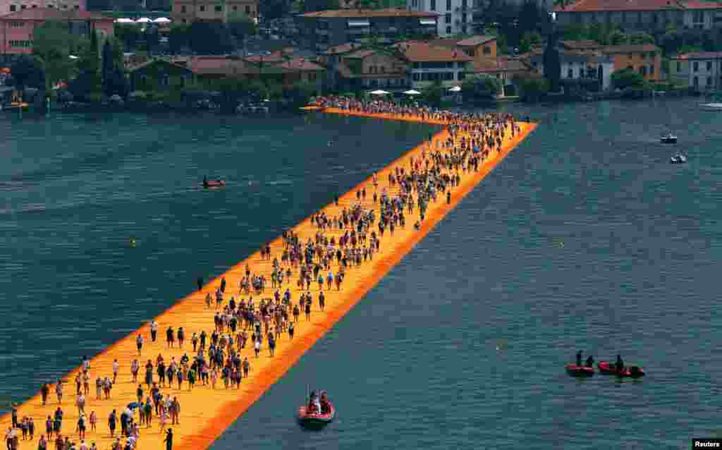 People walk on the installation 'The Floating Piers' by Bulgarian-born artist Christo Vladimirov Yavachev, known as Christo, on Lake Iseo, northern Italy.