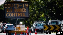 A COVID-19 signage is seen at a vehicle checkpoint on the Pacific Highway on the Queensland - New South Wales border in Brisbane on April 15, 2020. 