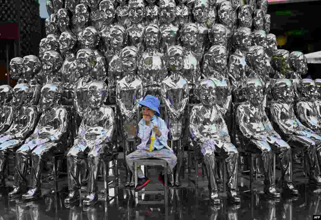 A boy sits on a chair amongst sculptures on display at a shopping center on International Children&#39;s Day in Beijing. China announced it would allow couples to have three children.