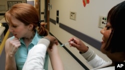 FILE - A woman is given a flu shot on the Emory University campus in Atlanta.