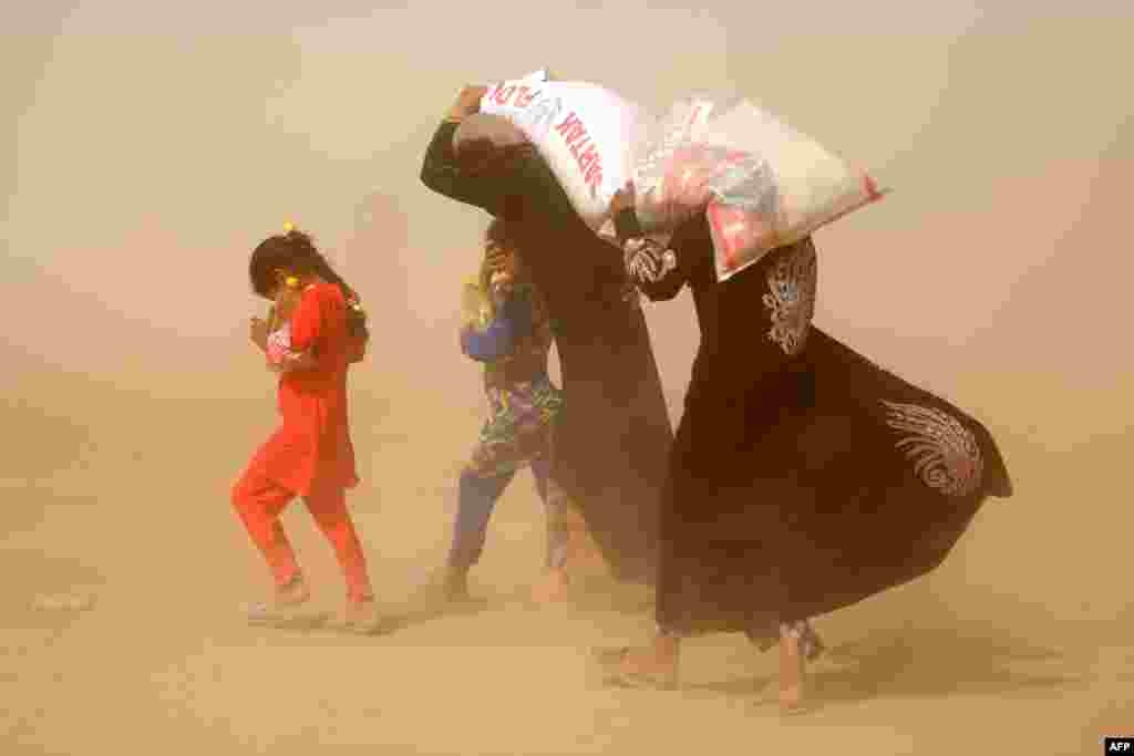 Displaced Iraqis, who fled the government's operation against the Islamic State (IS) group in the city of Fallujah, carry basic food items in a camp in Khaldiyeh, June 20, 2016.