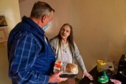 Meals on Wheels of Rhode Island driver Jim Stotler, left, delivers a meal to Rhonda Valoir, 66, at her apartment in Pawtucket, Nov. 20, 2020.