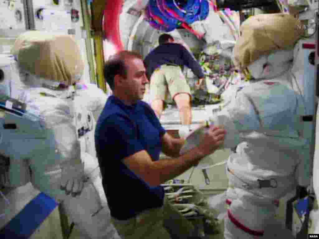 Astronaut Rick Mastracchio (L) checks out the spacesuit that he will wear during a spacewalk with crew member Mike Hopkins at the International Space Station in this undated image taken from video from NASA TV. 