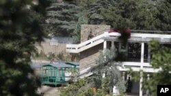 An Afghan policeman runs during a gun battle with militants outside of the Spozhmai Hotel on Lake Qurgha, where security officials say Taliban insurgents killed nearly two dozen people in an attack just north of Kabul, June 22, 2012. 