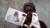 Une femme pose avec des drapeaux à l’effigie du pape François devant une église catholique à Maputo, Mozambique, le 31 août 2019.
