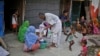 A Rohingya refugee distributes wheat, donated by locals, among other refugees at a camp for the refugees in New Delhi, India. 