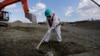 A worker, wearing a protective suit and a mask, levels ground at the tsunami-crippled Fukushima Dai-ichi nuclear power plant, operated by Tokyo Electric Power Co. (TEPCO), in Okuma, Fukushima Prefecture, northeastern Japan, Wednesday, Feb. 10, 2016.
