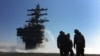 FILE - U.S. Navy deck crew stand near the island on the deck sprayed for radioactive decontamination aboard USS Ronald Reagan off the Japanese coast.