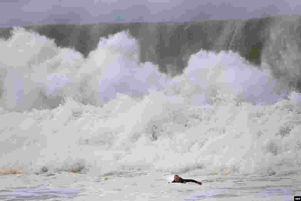 A surfer paddles back to shore when a huge wave crashes behind him at Narrabeen beach in Sydney's Northern Beaches, New South Wales, Australia.