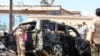 Pasukan keamanan Yaman dan tim penyelamat berkumpul di sekitar bangkai mobil yang terbakar menyusul ledakan yang melanda kota pelabuhan Aden di selatan Yaman, pada 10 Oktober 2021. (Foto: AFP)