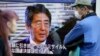 Passers-by look at a TV screen showing Japanese Prime Minister Shinzo Abe speak on North Korea's rocket launch, in Tokyo, Feb. 7, 2016.
