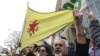 FILE - A man holds a flag of the YPG, a Syria-based Kurdish militant group, during a protest against Turkish President Recep Tayyip Erdogan in front of the Brookings Institution in Washington, where Erdogan was speaking, March 31, 2016.