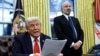 U.S. President Donald Trump reads about tariffs on steel and aluminum, as Howard Lutnick stands in the background, in the Oval Office of the White House in Washington, Feb. 10, 2025. 