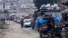 FILE - Syrians drive through the city of al-Mastouma, in Idlib province, as they flee a government offensive, Jan. 28, 2020.