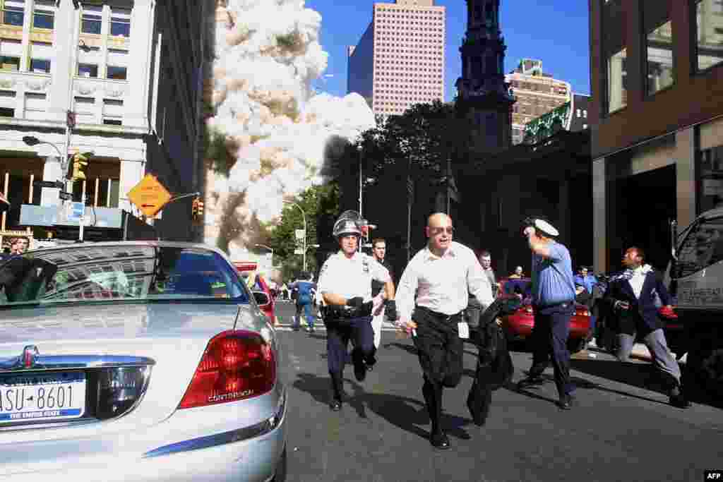 (FILE)&nbsp;Police and pedestrians run for cover during the first collapse of the World Trade Center Tower after the landmark skyscrapers were struck by two hijacked airplanes 11 September 2001 in New York . AFP PHOTO/Doug KANTER (Photo by DOUG KANTER / AFP)