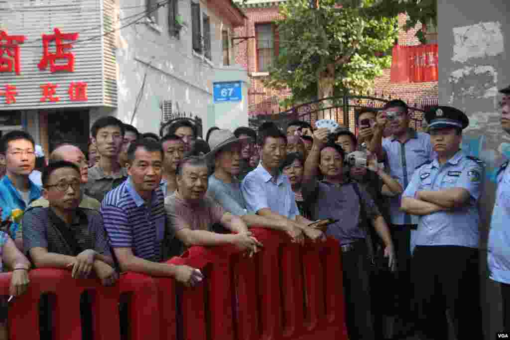 A supporter holds a placard during a rally behind a police barricade near the Jinan Intermediate People's Court, August 22, 2013. (Dongfang/VOA)