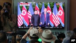 People watch a TV screen showing U.S. President Donald Trump, right, meeting with North Korean leader Kim Jong Un in Singapore during a news program at the Seoul Railway Station in Seoul, South Korea, June 12, 2018.