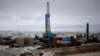 FILE - An oil derrick is seen at a fracking site outside of Williston, North Dakota.