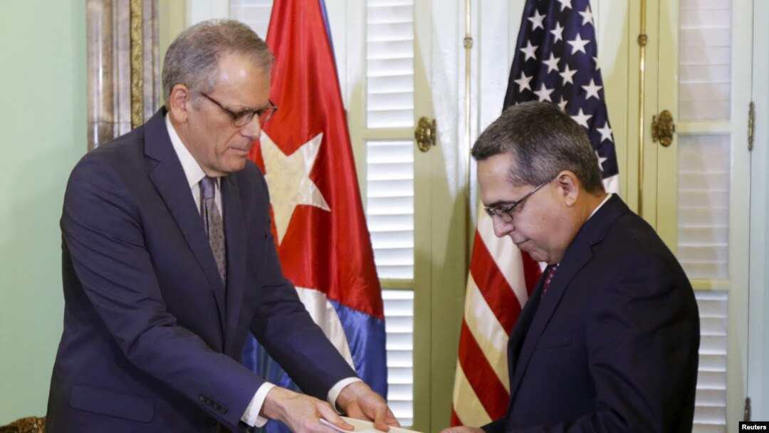 AQShning Kubadagi manfaatlariga javob beruvchi rasmiy Jeffri Delaurentis (chapda) Kuba Prezidenti Raul Kastroga Barak Obamaning elchixonalarni ochish haqidagi nomasini topshirmoqda, Gavana, Kuba, 1-iyul, 2015-yil