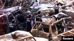 FILE - Indonesian forensic policemen walk past destroyed cars near the site of the Oct. 12, 2002, bomb blasts at Kuta on Indonesia's resort island of Bali, Oct. 18, 2002. 