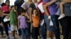 FILE - In this June 20, 2014 file photo, immigrants who entered the U.S. illegally stand in line for tickets at the bus station after they were released from a U.S. Customs and Border Protection processing facility in McAllen, Texas. 