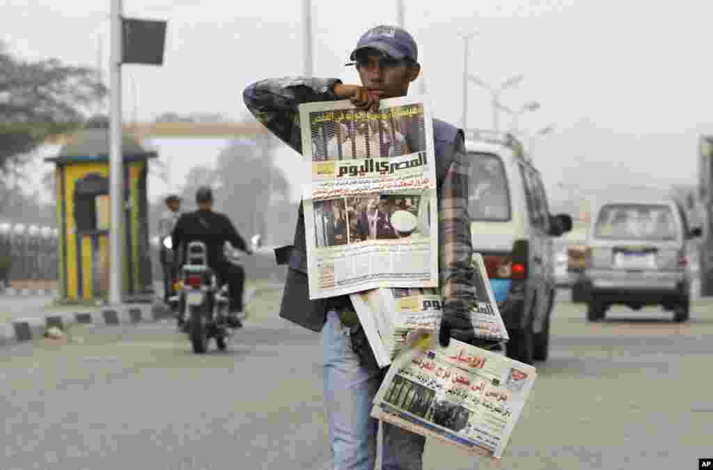 An Egyptian newspaper vendor in Cairo displays copies of the morning newspapers fronted by pictures of the trial of Egypt's ousted President Mohammed Morsi.
