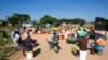 FILE - Women and children wait for their turn to fetch water in a poor suburb of Harare, Zimbabwe, March, 31, 2020.