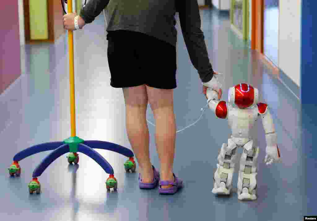 Belgian Ian Frejean, 11, walks with, Zora the robot, a humanoid robot designed to entertain patients and to support care providers, at AZ Damiaan hospital in Ostend, Belgium.