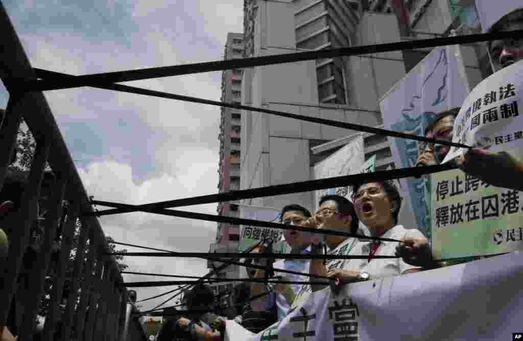 Pro-democracy protesters display black ribbons in front of the Chinese central government's liaison office in Hong Kong. One of the five Hong Kong booksellers whose disappearances sparked international concern said Thursday he spent months confined in a room under constant surveillance by mainland Chinese authorities.