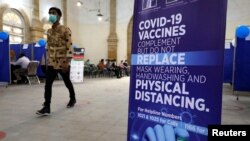 A man walks past an awareness sign inside the Khaliq Dina Hall and Library, which has been converted to COVID-19 vaccination center, in Karachi, Pakistan, Feb. 1, 2021.
